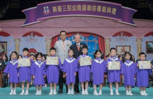东华三院主席兼校监李鋈麟博士太平绅士（左）陪同主礼嘉宾香港大学教育学院谢锡金教授（右）颁发毕业证书予幼稚园毕业学生代表。
