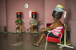 麦永接医生于古巴拍摄的照片，照片内的女士在发廊中大方地接受陌生人的拍照，神情自信，流露着自然美。