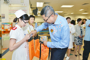 东华三院主席施荣恒先生（右一）巡视广华医院门诊部卖旗摊位，并感谢协助卖旗的医护及行政人员。