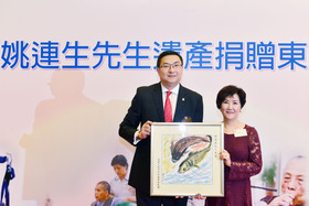 施荣恒主席（左）于捐赠仪式上致送由本院视障长者亲手绘画的挂画予姚连生夫人。