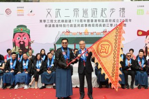民政事务局局长刘江华太平绅士（右）颁授巡游出发令旗予东华三院主席李鋈麟博士太平绅士（左），象征巡游正式开始。