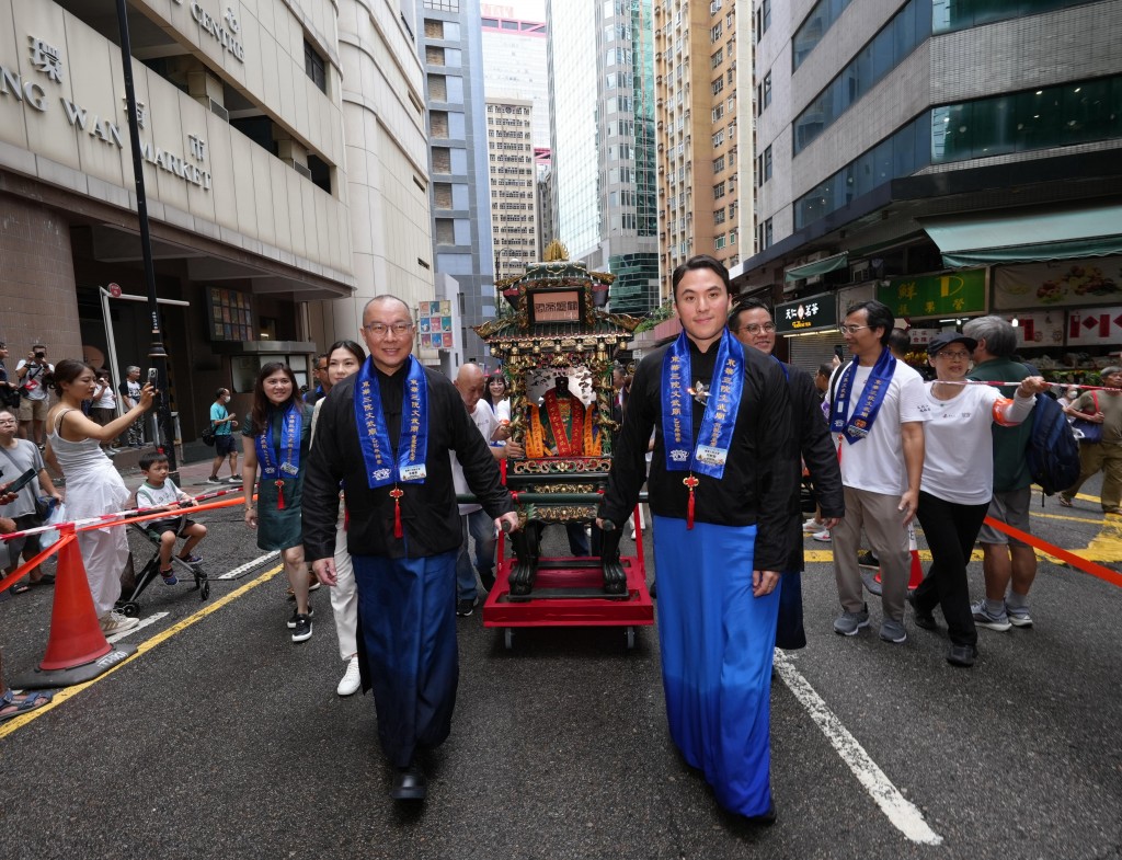 图三为东华三院主席何猷启先生（前排右）联同董事局成员随文武二帝銮舆出巡，吸引途人驻足观赏。