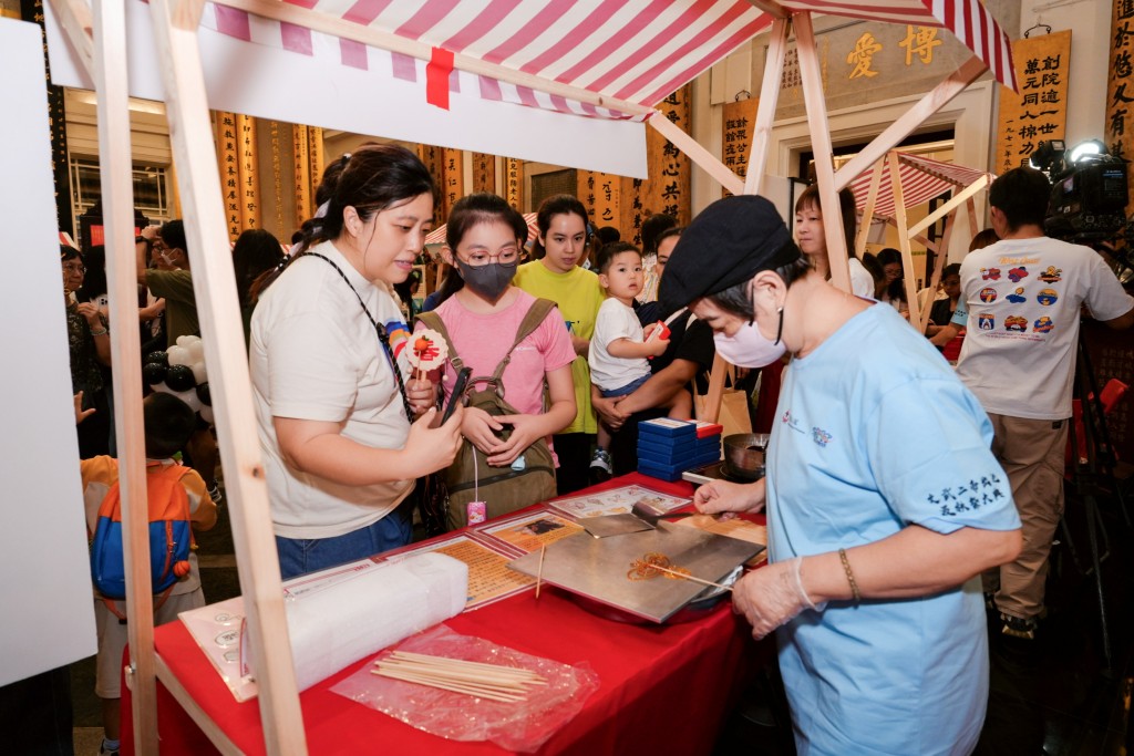 图九为活动当天下午设有多个中华文化摊位，图中市民正体验制作传统「糖画」感受非物质文化遗产的乐趣。 