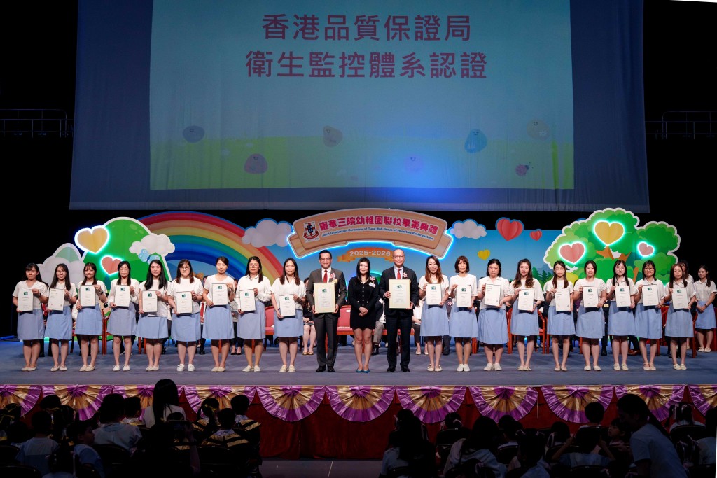图五为香港质量保证局业务助理总经理何晓彤女士(中)颁发衞生监控体系认证证书,由本院主席兼校监曾庆业先生(右十)及学务委员会主任委员李旷怡副主席(左十)联同18所幼稚园教师代表接受。
